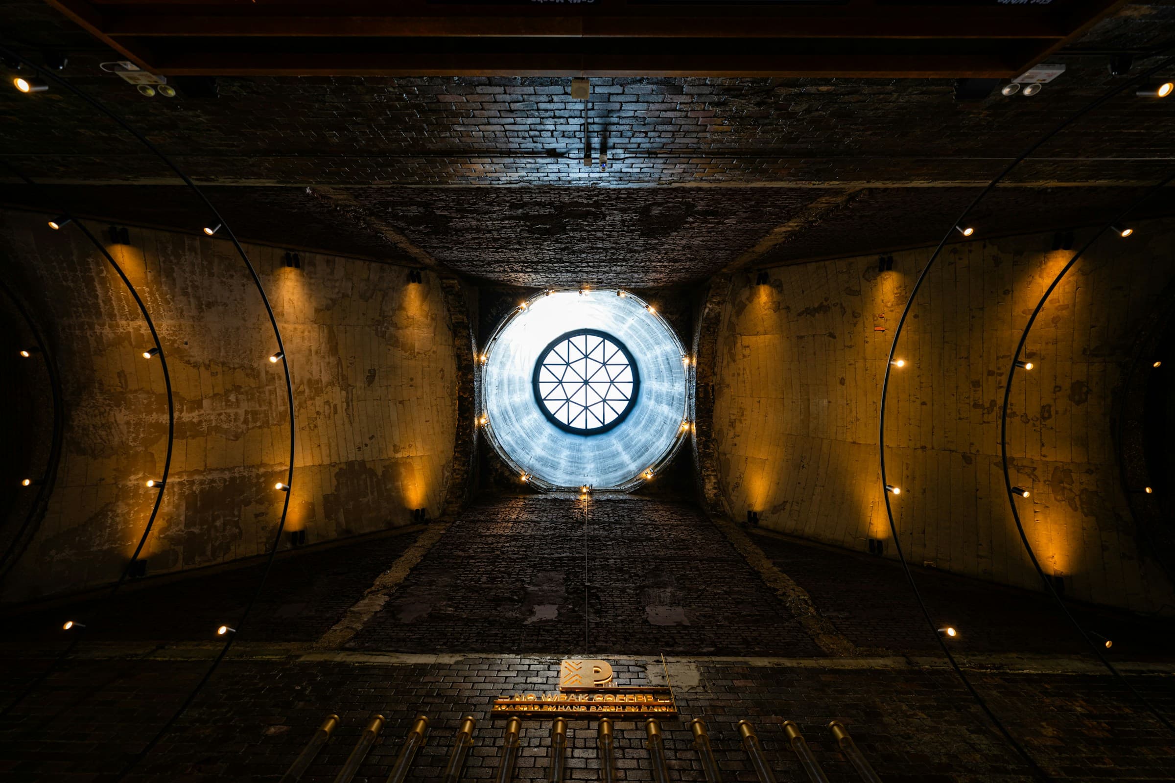 Arched dark room interior with a single circular skylight — a quiet space where opposites meet