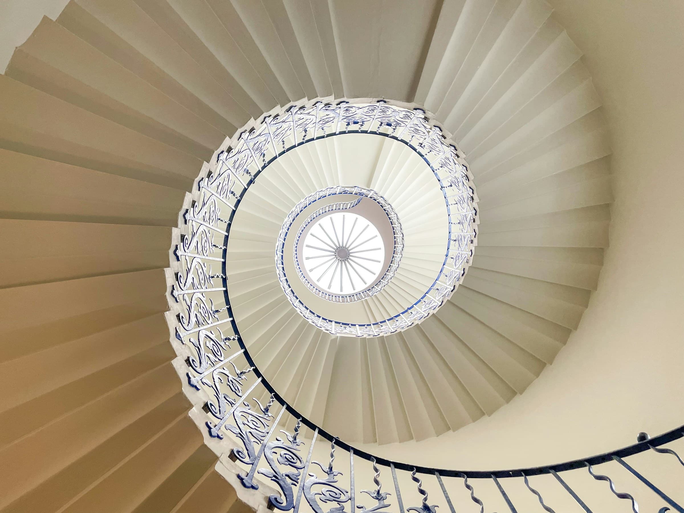 Spiral staircase viewed from below, with a luminous central skylight